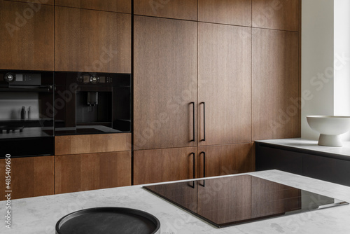 Modern minimalistic kitchen with black and wooden surfaces, marble kitchen island top and household appliances. Modern Concept For Interior Design And Architecture.
