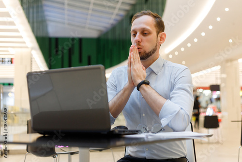Young businessman practicing breathing exhalation exercises working online to manage stress and calm down photo
