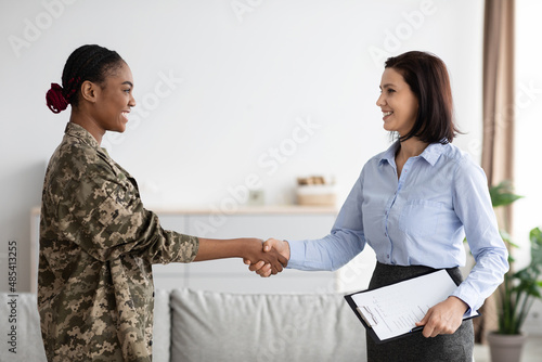 Female Therapist And Happy Black Soldier Woman Handshaking In Office After Meeting photo