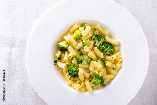 pasta with broccoli on a white plate and white ceramic background.