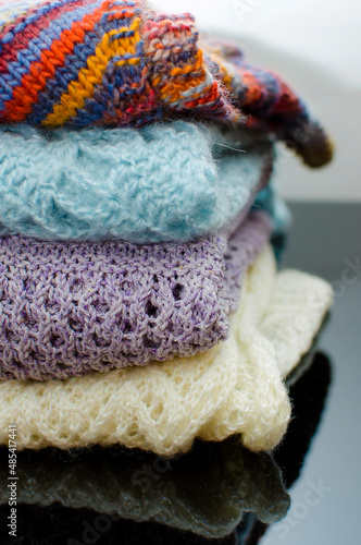 Stack of cozy knitted autumn and winter sweaters on a neutral background. Concept of warmth and comfort clothes. Vertical photography. photo