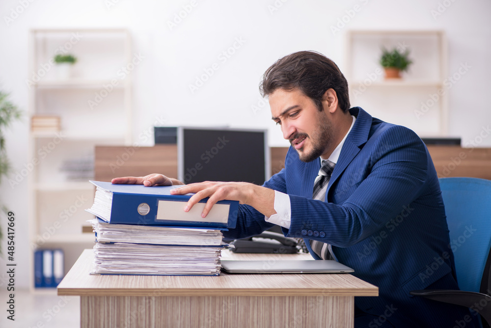Young male employee and too much work in the office Young male employee and too much work in the office