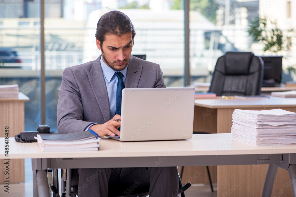 Young male employee in wheel-chair working in the office Young male employee in wheel-chair working in the office