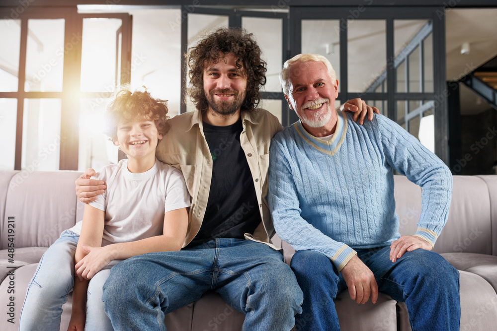 Grandfather, father e grandchild that enjoy together on sofa at home