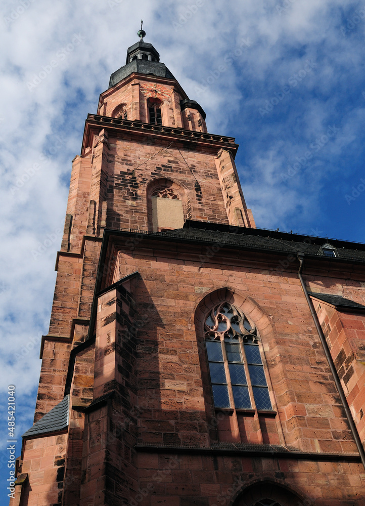 Fototapeta premium The Facade Of The Cathedral's Bell Tower In Heidelberg Germany On A Beautiful Sunny Summer Day With A Clear Blue Sky And A Few Clouds