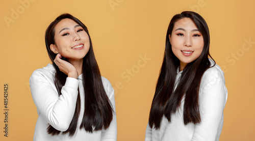 Asian girls twin sisters with healthy shine long hair posing on yellow studio background. Haircare cosmetics advertising