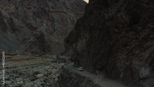 Aerial view of a car going on a road in the rocky mountains 