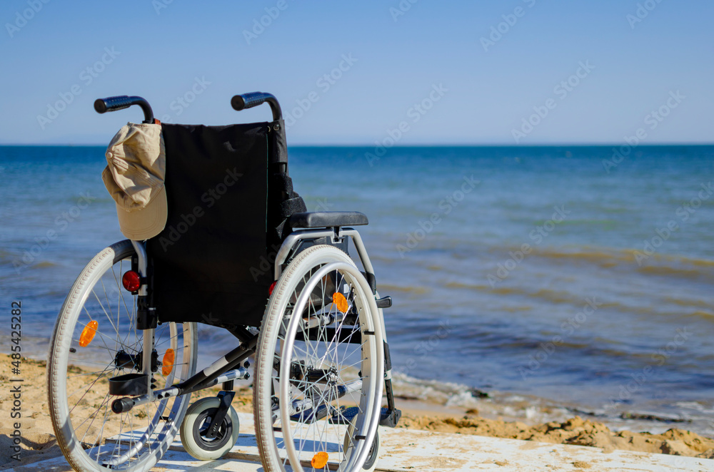 Fototapeta premium wheelchair on the seashore. disabled person resting on the sea