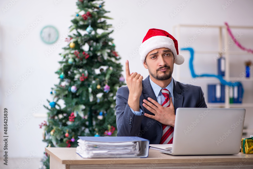 Young male employee celebrating Christmas at workplace Young male employee celebrating Christmas at workplace
