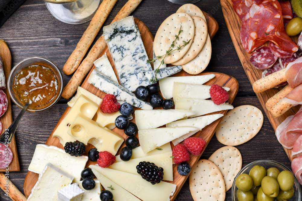 Сheese board with different types of Italian and French cheese gorgonzola parmesan brie or camembert and maasdam, serving with blueberry and raspberries, with jam crackers and grissini breadsticks