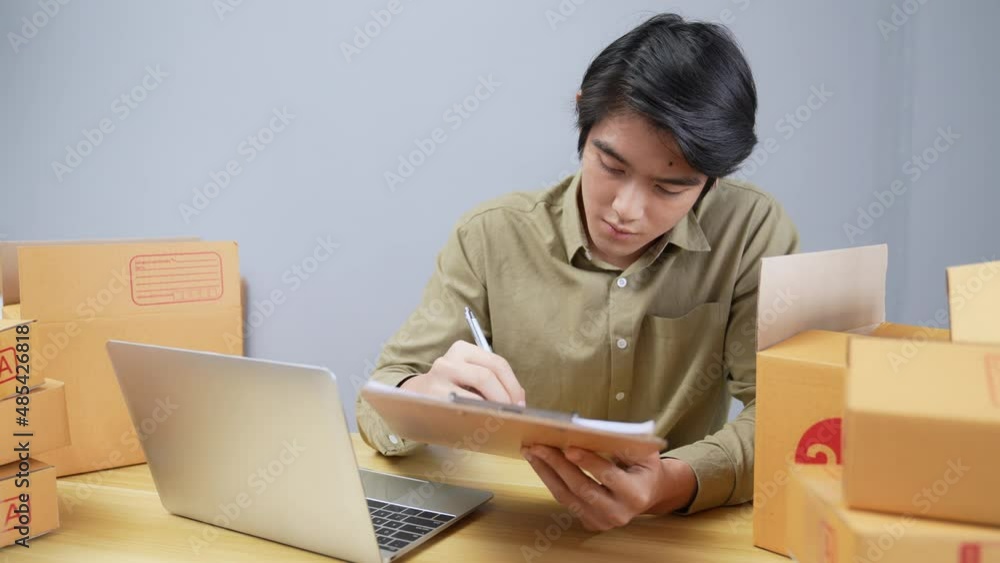 Business concept of 4k Resolution. Young Asian man checking online customer orders in office. Business concept of 4k Resolution. Young Asian man checking online customer orders in office.