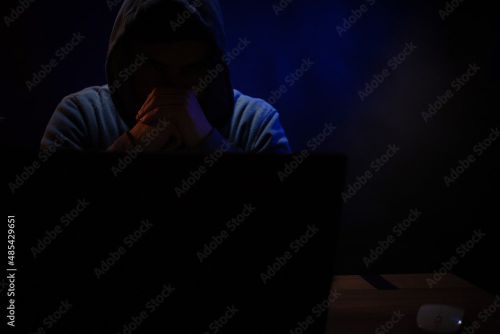 Hacker near front of computer laptop. Man hacker in dark room Hacker near front of computer laptop. Man hacker in dark room