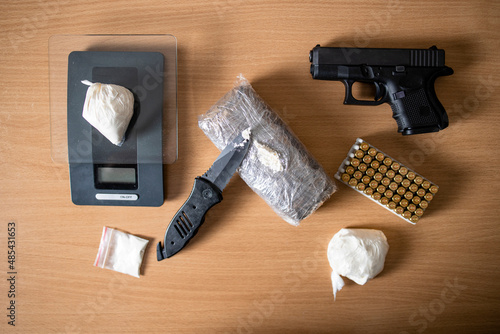 Criminal activity and drugs or narcotics ready for street distribution and sale. Top view of packages with cocaine, gun, ammunition and scale.