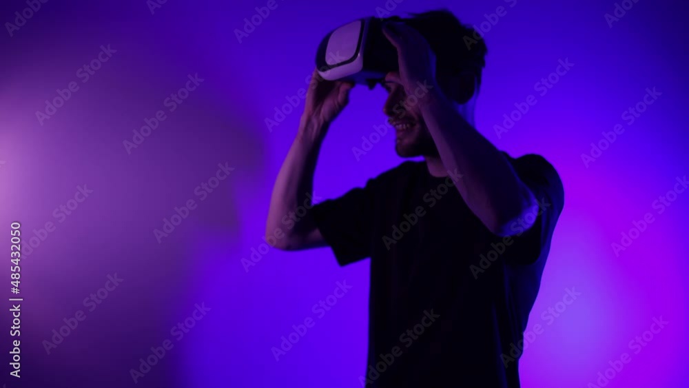 Man in metaverse using VR virtual reality glasses. Futuristic universe games and future in digital technology. Entreatment and NFT in neon colorful space. Happy male. Slow motion video in 3d cyber. Man in metaverse using VR virtual reality glasses. Futuristic universe games and future in digital technology. Entreatment and NFT in neon colorful space. Happy male. Slow motion video in 3d cyber.