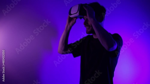 Man in metaverse using VR virtual reality glasses. Futuristic universe games and future in digital technology. Entreatment and NFT in neon colorful space. Happy male. Slow motion video in 3d cyber.