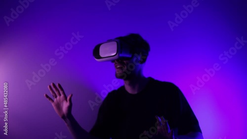Man in metaverse using VR virtual reality glasses. Futuristic universe games and future in digital technology. Entreatment and NFT in neon colorful space. Happy male. Slow motion video in 3d cyber.
