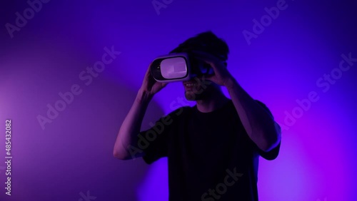 Man in metaverse using VR virtual reality glasses. Futuristic universe games and future in digital technology. Entreatment and NFT in neon colorful space. Happy male. Slow motion video in 3d cyber.