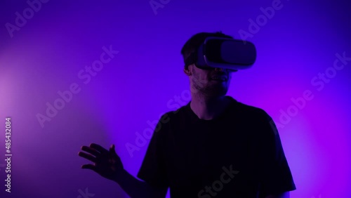Man in metaverse using VR virtual reality glasses. Futuristic universe games and future in digital technology. Entreatment and NFT in neon colorful space. Happy male. Slow motion video in 3d cyber.