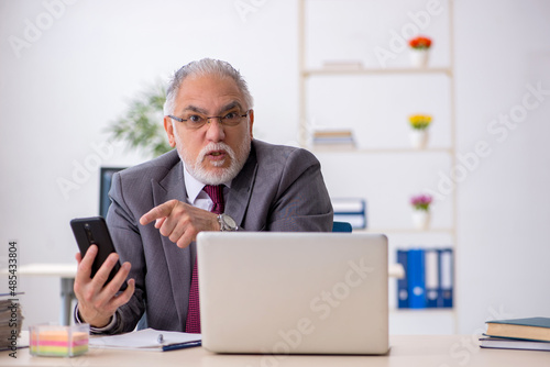 Old male employee sitting in the office