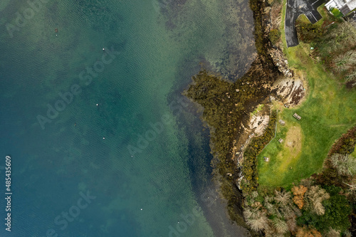 Aerial top down view on a small picnic area by the ocean. Wooden tables and seat. Blue color water. Roundstone, county Galway, Ireland