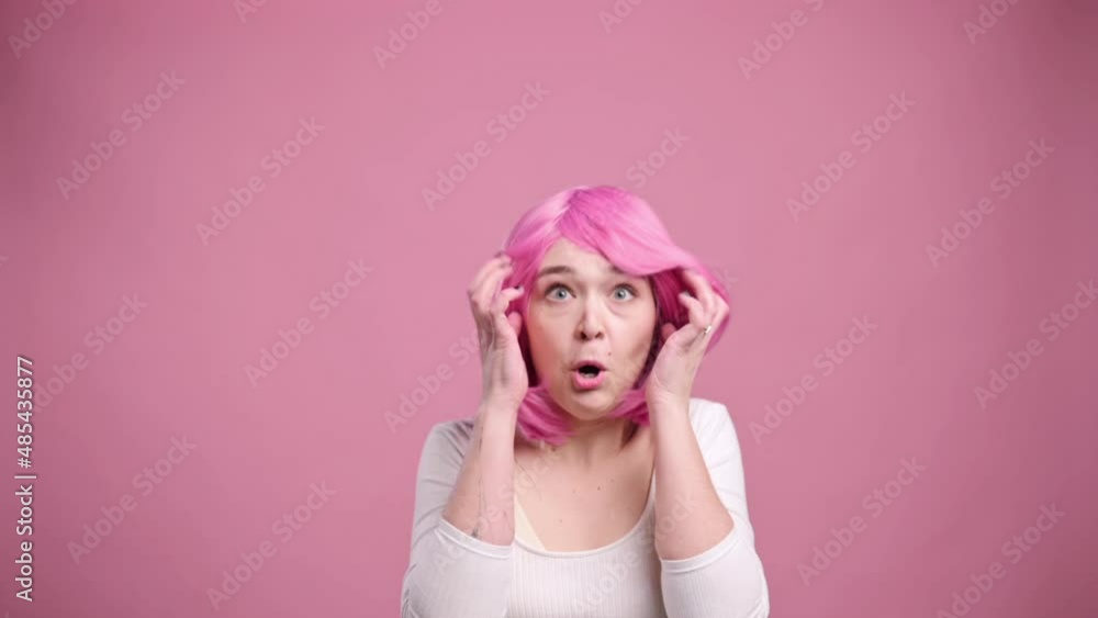 Portrait of shocked woman on pink background. Young female in pink wig has her head boiled. Portrait of shocked woman on pink background. Young female in pink wig has her head boiled.