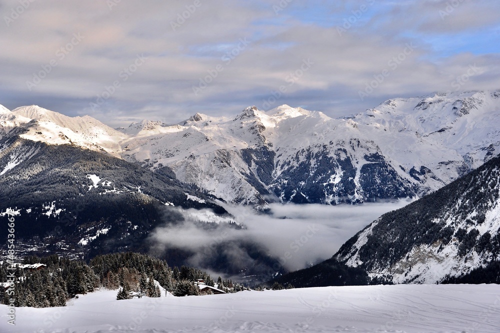 Snowcapped Mountain View from the ski slope with clouds over the  valley 