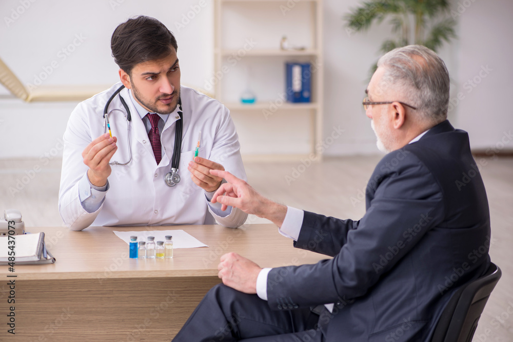 Obraz premium Old businessman visiting young male doctor in vaccination concep
