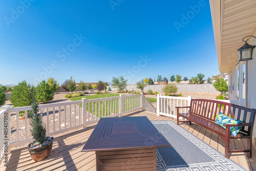 Deck of a house with potted pine tree near the fire pit table and bench with carpet in the middle
