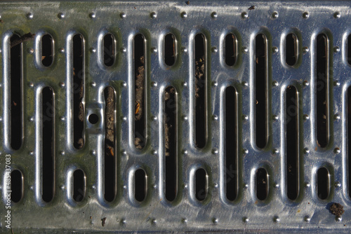 Full frame close-up view of a segment of a steel drain cover on a sidewalk