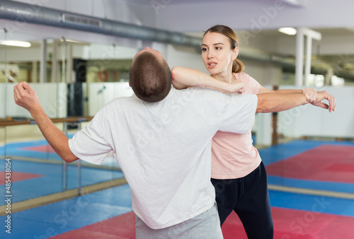 Active girl conducts painful grip on self-defense training in the gym