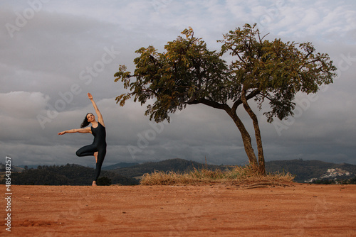 Woman doing yoga exercise asana on a top of a mountain.