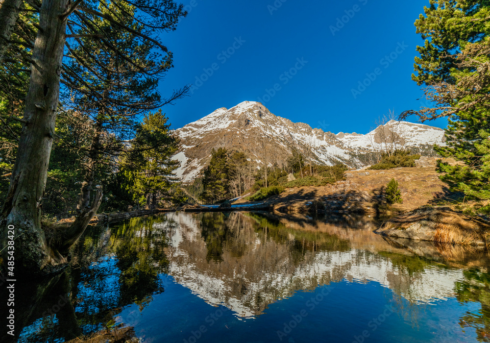 Snowy mountain reflected on the water of a lake in the Pyrenees, Spain. Mountain landscape.