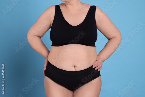 Overweight woman in underwear on light blue background, closeup © New Africa