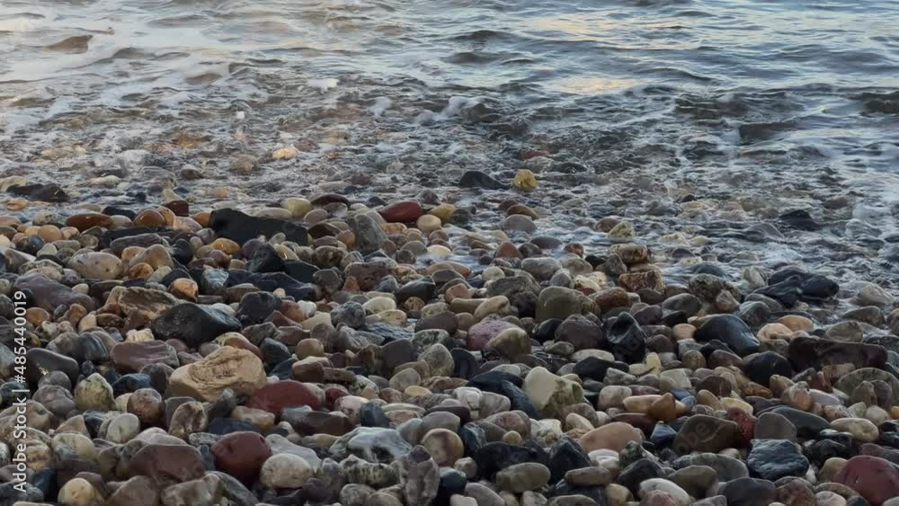Pebble beach. Waves, surf. Stony coastline. Water of sea, ocean, river or lake. Pebble beach. Waves, surf. Stony coastline. Water of sea, ocean, river or lake.