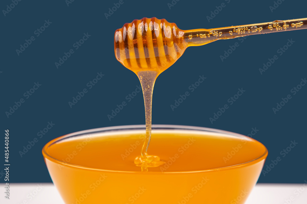 fresh fragrant honey drips from a spoon into a plate on a colored background. organic vitamin nutrition. dessert food fresh fragrant honey drips from a spoon into a plate on a colored background. organic vitamin nutrition. dessert food