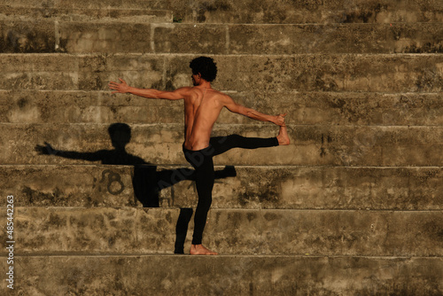 Man doing yoga fitness sport in the streets with stairs background