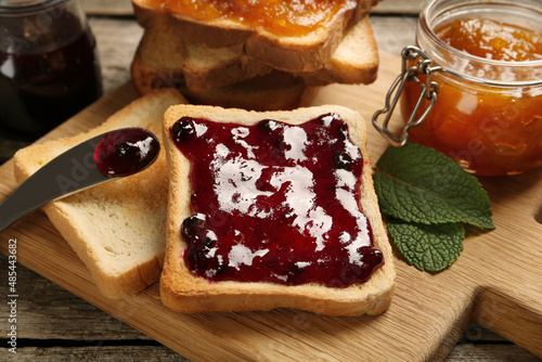 Delicious toasts with jam on wooden board, closeup