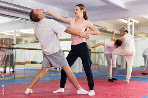 Woman and man practicing self defense techniques in gym
