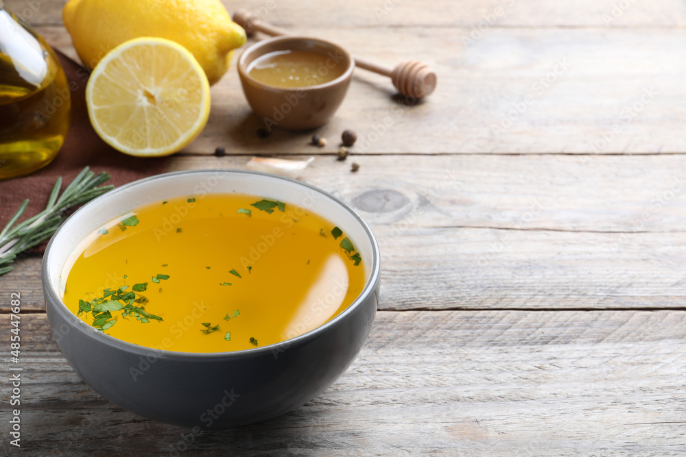 Bowl with lemon sauce and ingredients on wooden table, space for text. Delicious salad dressing Bowl with lemon sauce and ingredients on wooden table, space for text. Delicious salad dressing
