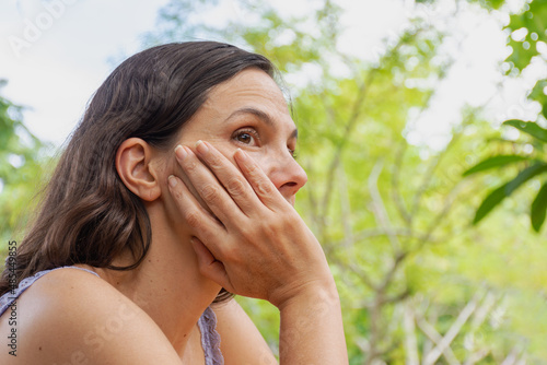 Mulher com mão no rosto pensativa