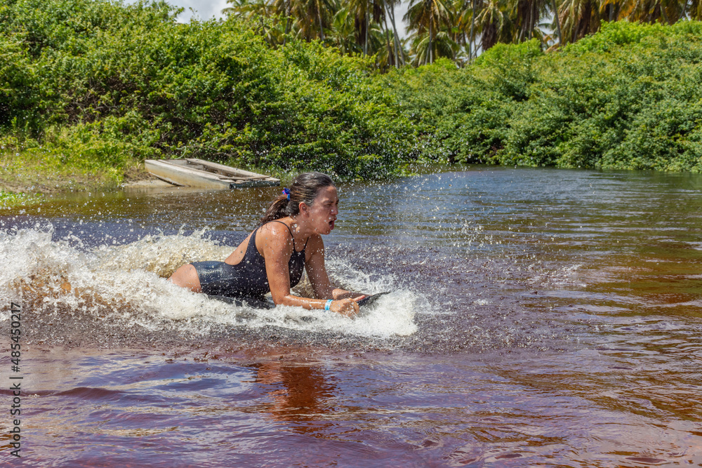 Fototapeta premium Mulher deslizando numa prancha sob agua num rio