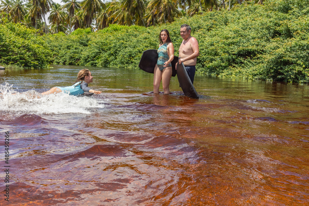 Pai e mãe observam filha se divertindo na água Pai e mãe observam filha se divertindo na água