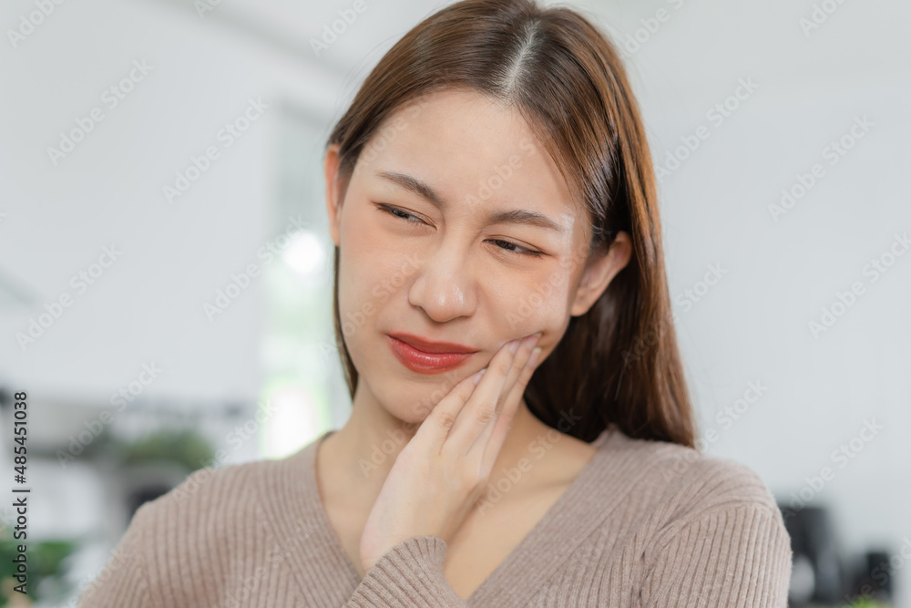 Closing eyes asian young woman touching cheek, face expression from toothache, tooth decay or sensitivity, Having tooth or teeth problem or inflammation, suffering from health. Sensitive teeth people