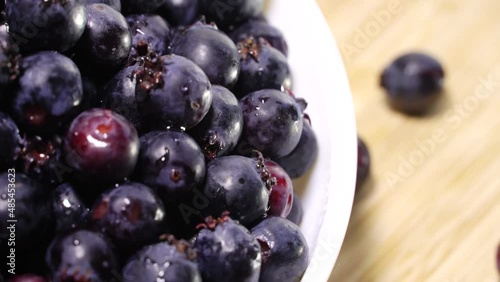 Fresh juicy serviceberries in a white bowl, rotation background