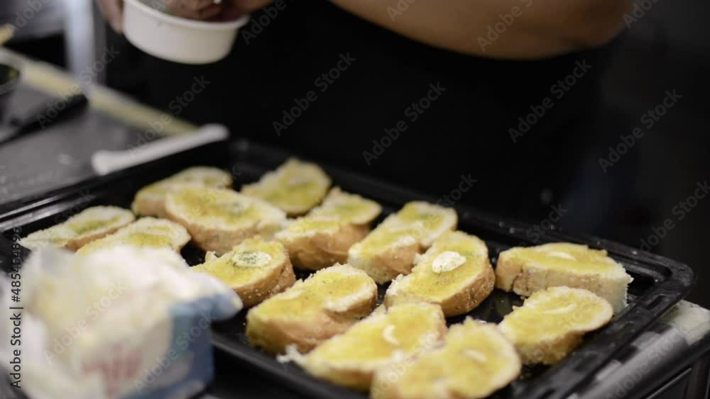 Woman chef cook adding spices to garlic buttered bread at a local diner cafe restaurant in Mexico Latin america Woman chef cook adding spices to garlic buttered bread at a local diner cafe restaurant in Mexico Latin america