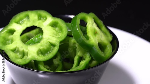 Sliced green bell peppers in a black bowl rotation