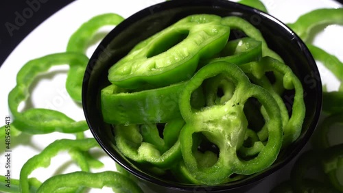 Chopped green bell peppers in a black bowl rotation