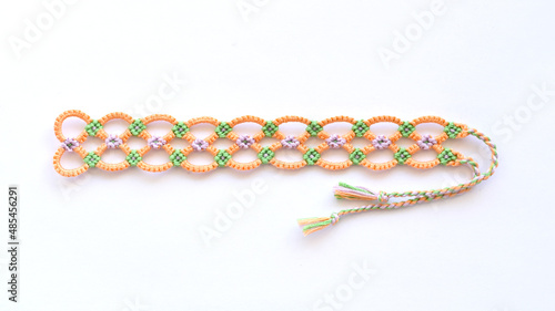 Tied DIY friendship bracelet with unusual braiding pattern on white background