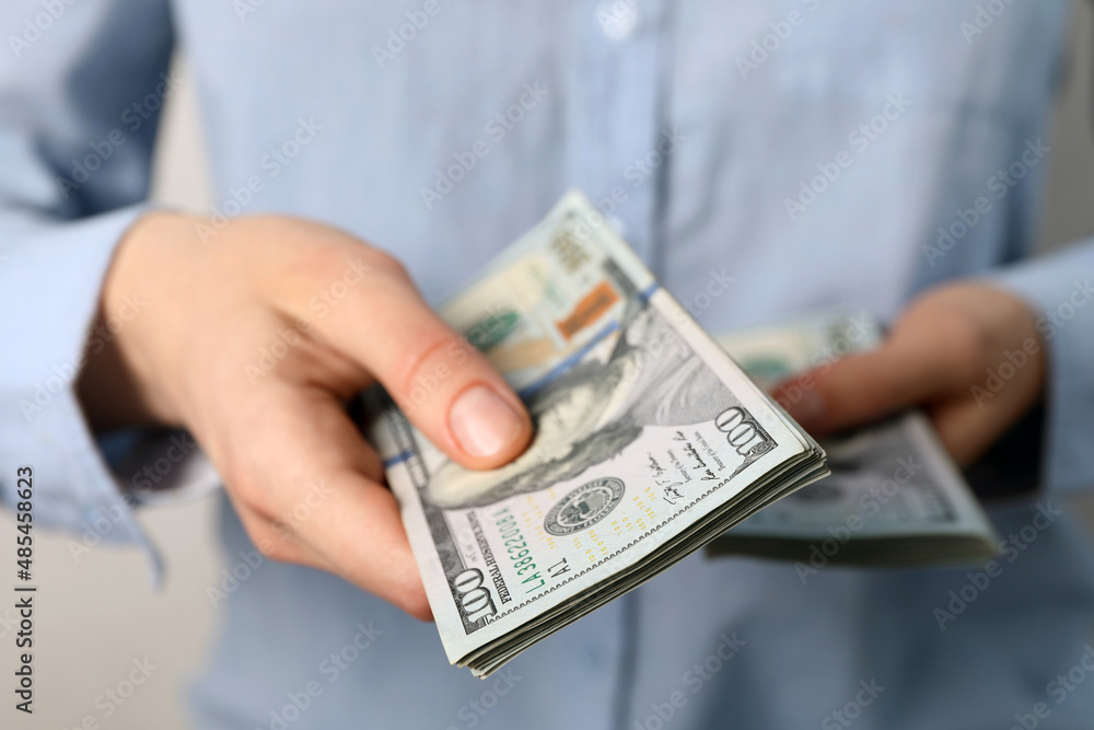 Woman counting dollar banknotes on light background, closeup Woman counting dollar banknotes on light background, closeup