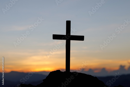 Silhouettes of crucifix symbol on top mountain with bright sunbeam on the colorful sky background